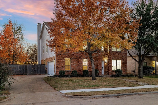 obstructed view of property featuring brick siding, an attached garage, fence, and driveway