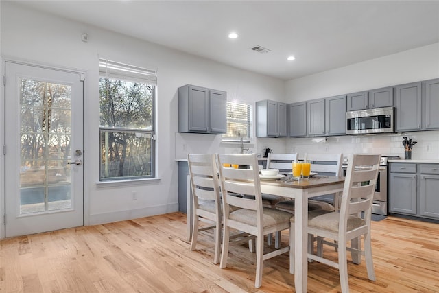 dining room featuring baseboards, light wood-style flooring, visible vents, and recessed lighting