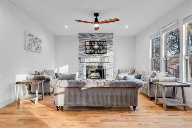living room featuring a fireplace, light wood-style flooring, a ceiling fan, and recessed lighting