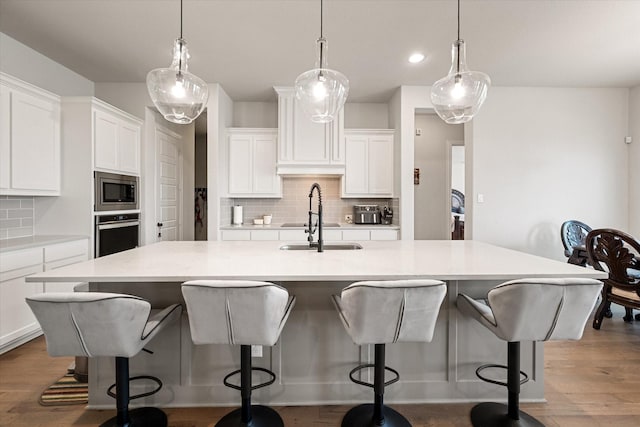 351 Evening Fire Dr, Waxahachie, TX 75167 - kitchen with a sink, decorative backsplash, a kitchen island with sink, white cabinets, and appliances with stainless steel finishes