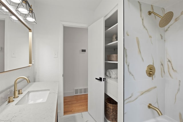full bath with visible vents, vanity, and a marble finish shower