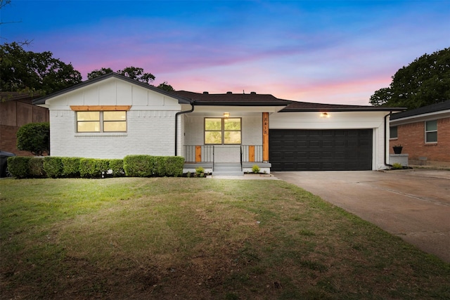 ranch-style home featuring an attached garage, driveway, covered porch, a lawn, and brick siding