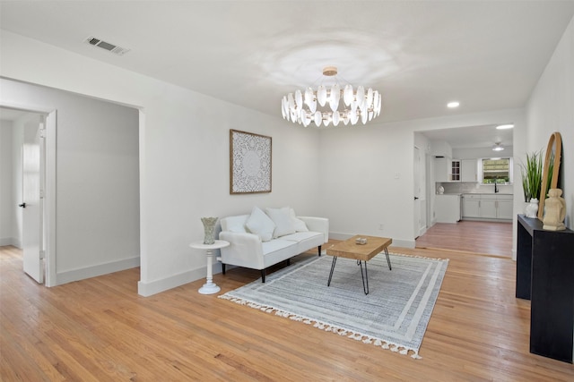 living area featuring recessed lighting, light wood finished floors, an inviting chandelier, visible vents, and baseboards