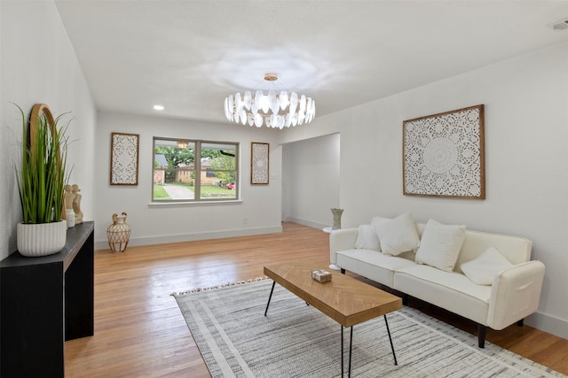living room featuring visible vents, baseboards, light wood-style floors, and a chandelier
