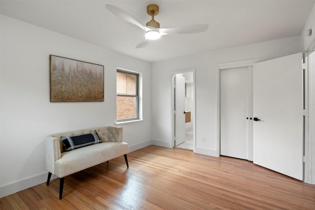 living area with light wood finished floors, a ceiling fan, and baseboards