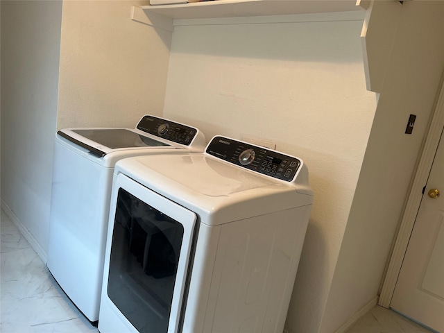 clothes washing area featuring laundry area, washing machine and dryer, baseboards, and marble finish floor