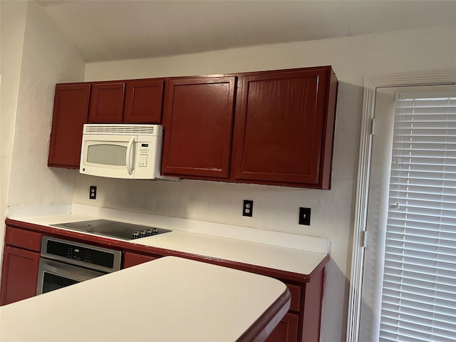 kitchen featuring light countertops, black electric stovetop, white microwave, and oven