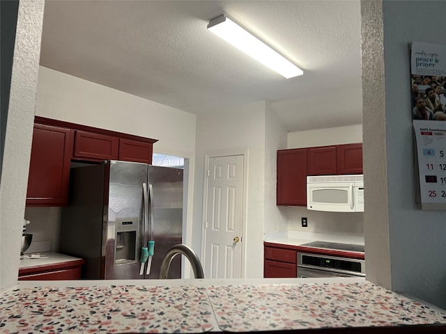 kitchen with dark brown cabinets, light countertops, a textured ceiling, a sink, and stainless steel appliances