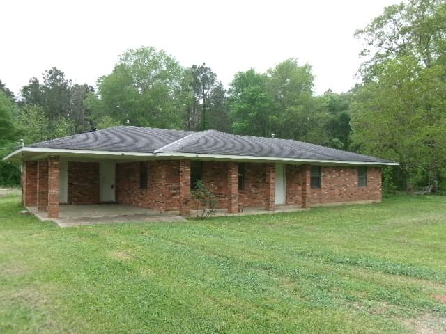 rear view of house featuring brick siding and a lawn