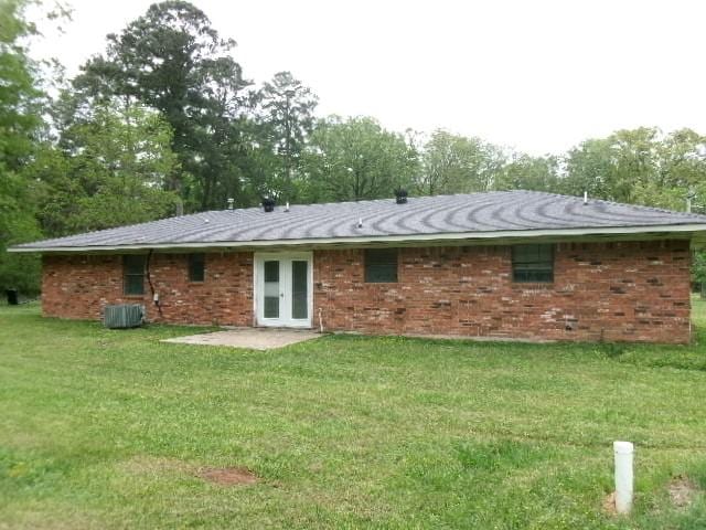 back of property featuring central air condition unit, brick siding, a yard, and french doors