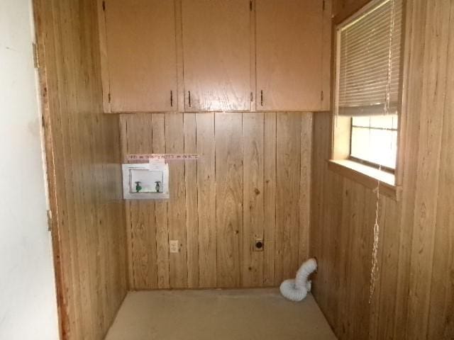 clothes washing area featuring hookup for an electric dryer, cabinet space, hookup for a washing machine, and wooden walls
