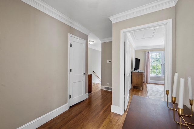 hall featuring wood finished floors, ornamental molding, an upstairs landing, baseboards, and attic access