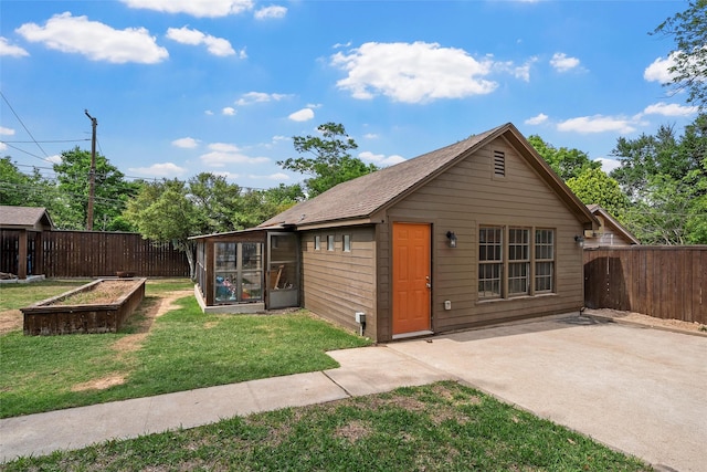 view of front of home with a front lawn, a garden, a patio, and fence private yard