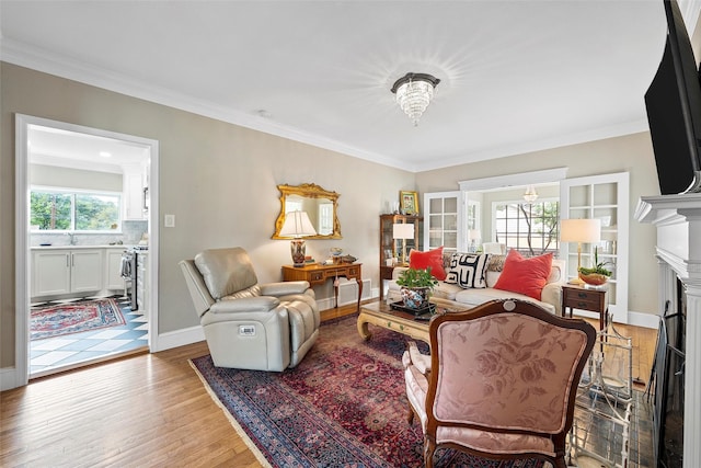 living room featuring a fireplace, light wood-style flooring, crown molding, and baseboards