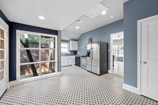 kitchen featuring lofted ceiling, stainless steel appliances, visible vents, baseboards, and white cabinetry