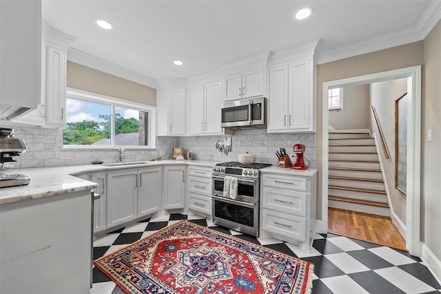 kitchen with a wealth of natural light, appliances with stainless steel finishes, tile patterned floors, and a sink