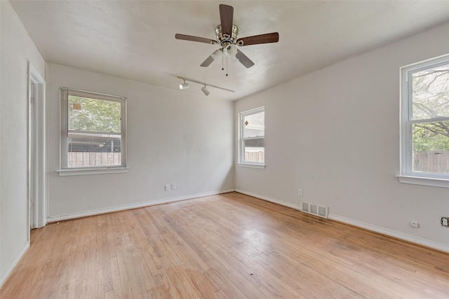 spare room with light wood-style flooring, visible vents, a wealth of natural light, and rail lighting