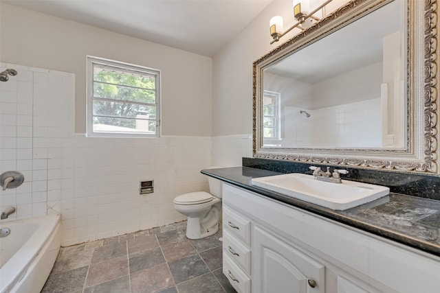full bathroom featuring stone finish floor, toilet, vanity, tub / shower combination, and tile walls