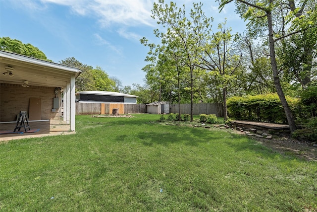 view of yard with a fenced backyard, an outbuilding, and a storage shed