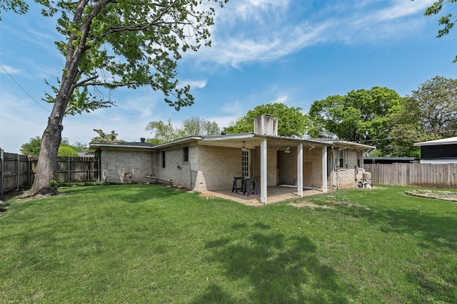 rear view of property with a patio area, a fenced backyard, a chimney, and a yard