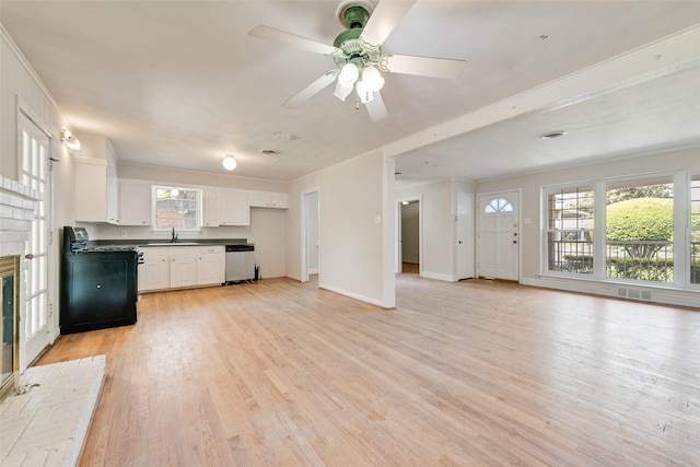 unfurnished living room with crown molding, a ceiling fan, a sink, and light wood-style flooring