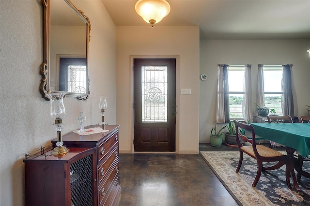 foyer entrance with concrete flooring, a healthy amount of sunlight, and baseboards