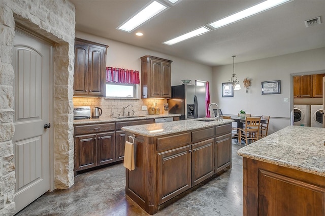 kitchen with visible vents, washer and dryer, stainless steel fridge, and a sink