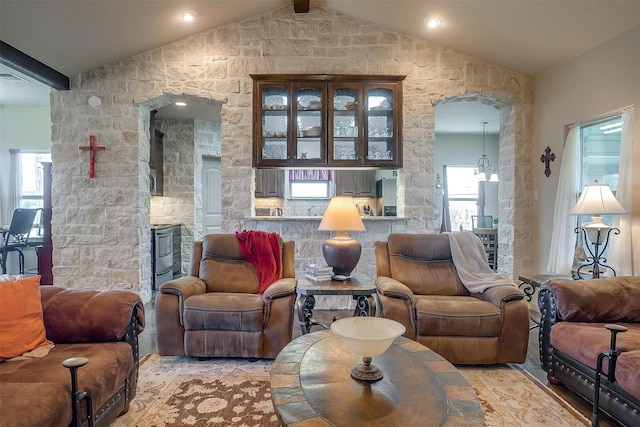 living area with lofted ceiling with beams, visible vents, arched walkways, and a healthy amount of sunlight
