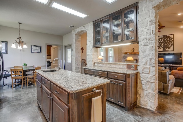 kitchen featuring glass insert cabinets, pendant lighting, a sink, and finished concrete flooring