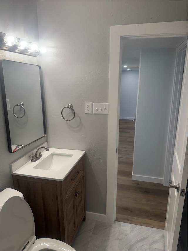 bathroom featuring toilet, baseboards, and vanity