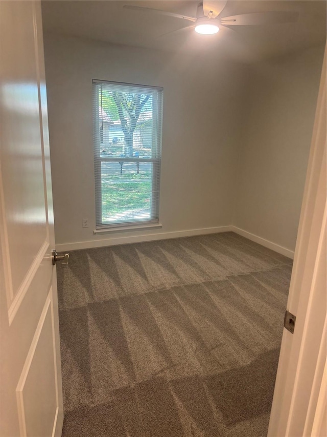empty room featuring dark carpet, ceiling fan, and baseboards
