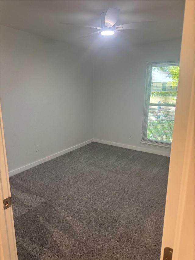 unfurnished room with dark colored carpet, baseboards, and ceiling fan
