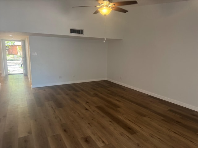 unfurnished room with baseboards, visible vents, dark wood-style floors, and ceiling fan