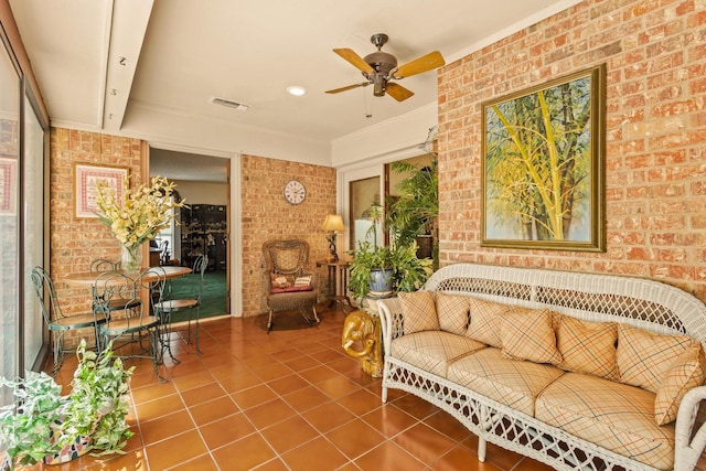 sitting room featuring brick wall, a ceiling fan, tile patterned floors, and visible vents