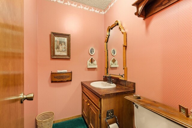half bathroom featuring wallpapered walls and vanity
