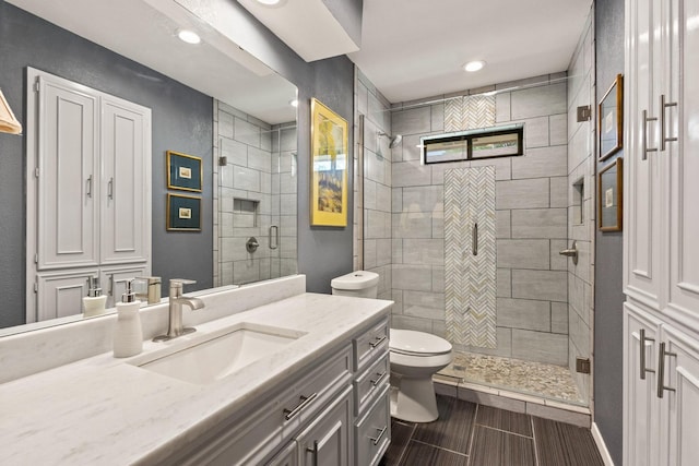 bathroom featuring a shower stall, wood finish floors, vanity, toilet, and recessed lighting