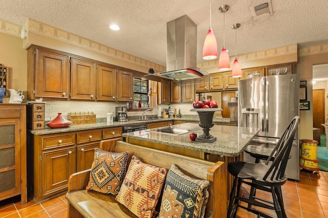 kitchen featuring island exhaust hood, stainless steel fridge, a textured ceiling, brown cabinetry, and black electric stovetop