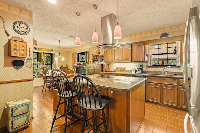 kitchen with a center island, island exhaust hood, a sink, wallpapered walls, and brown cabinetry