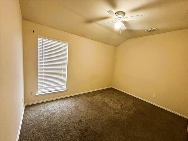 4303 Grassy Glen Dr, Corinth, TX 76208 - empty room with dark carpet, ceiling fan, baseboards, lofted ceiling, and healthy amount of natural light
