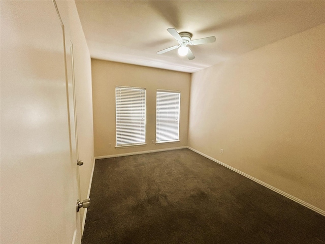 empty room with baseboards, dark carpet, and ceiling fan