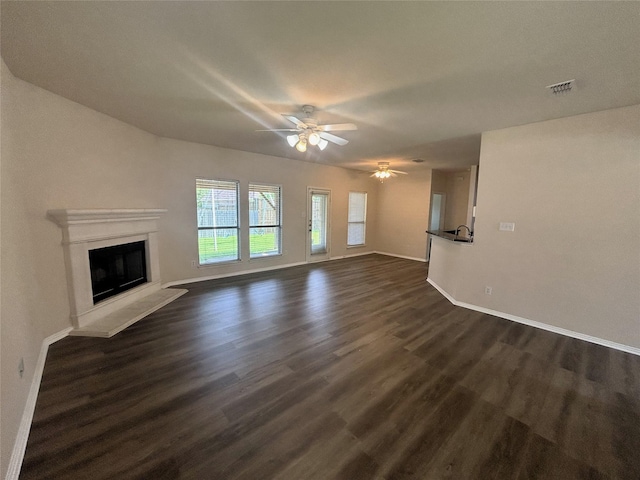 4303 Grassy Glen Dr, Corinth, TX 76208 - unfurnished living room featuring dark wood-type flooring, baseboards, a ceiling fan, and a glass covered fireplace