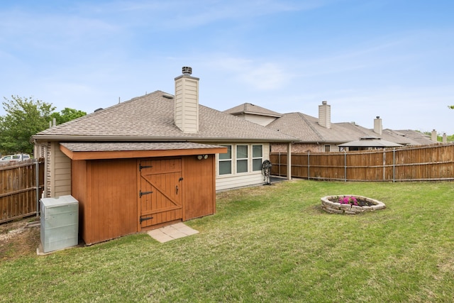 601 Wichita Trl, Mckinney, TX 75071 - rear view of property featuring a chimney, an outdoor fire pit, a fenced backyard, a shingled roof, and a lawn