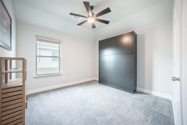 unfurnished bedroom featuring carpet floors, a closet, baseboards, and ceiling fan