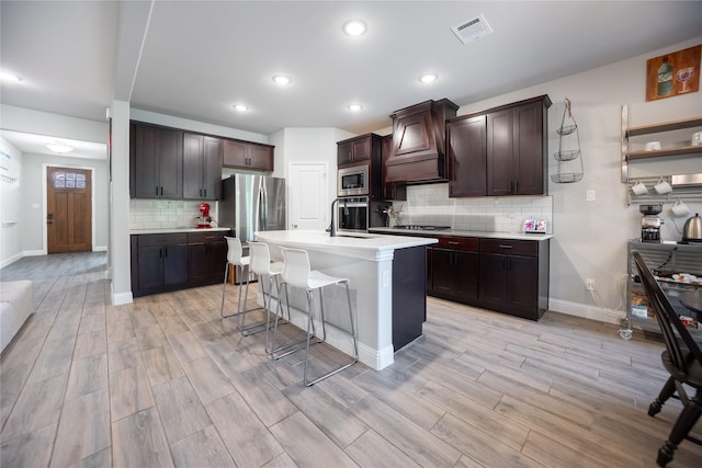 kitchen featuring light countertops, visible vents, decorative backsplash, appliances with stainless steel finishes, and custom exhaust hood
