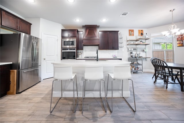 kitchen with stainless steel appliances, visible vents, premium range hood, a chandelier, and tasteful backsplash