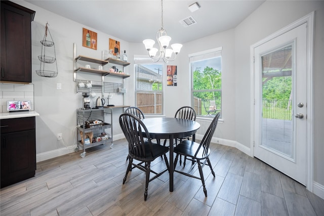 dining area featuring visible vents, light wood-style flooring, baseboards, and an inviting chandelier