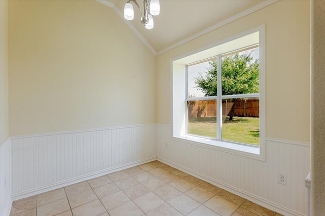 spare room with a wainscoted wall, a notable chandelier, lofted ceiling, crown molding, and light tile patterned floors