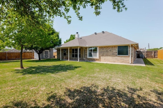 back of house featuring a patio area, a storage shed, a lawn, a fenced backyard, and an outbuilding
