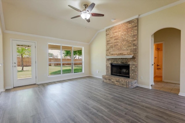 unfurnished living room featuring arched walkways, lofted ceiling, wood finished floors, and ceiling fan
