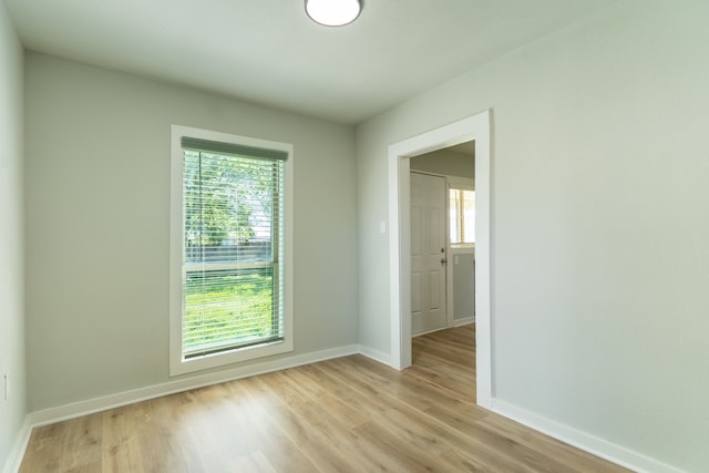 empty room with plenty of natural light, baseboards, and light wood-style flooring